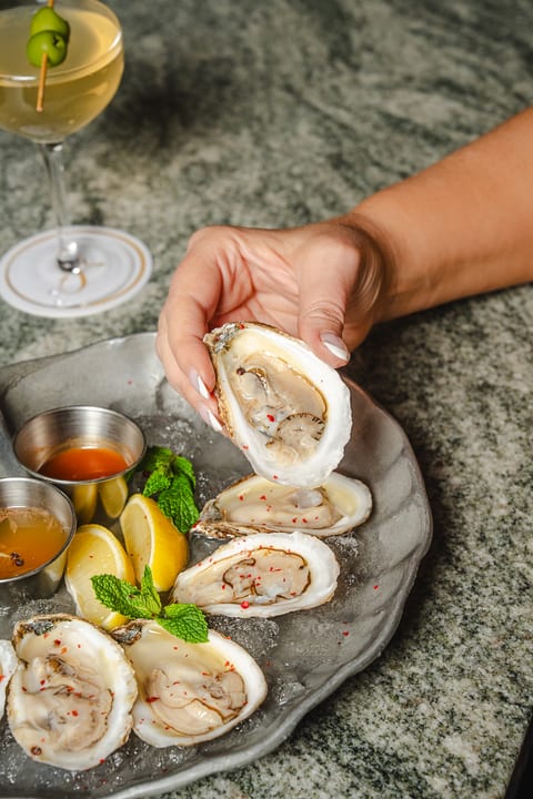 Hand holding a fresh oyster on the half shell