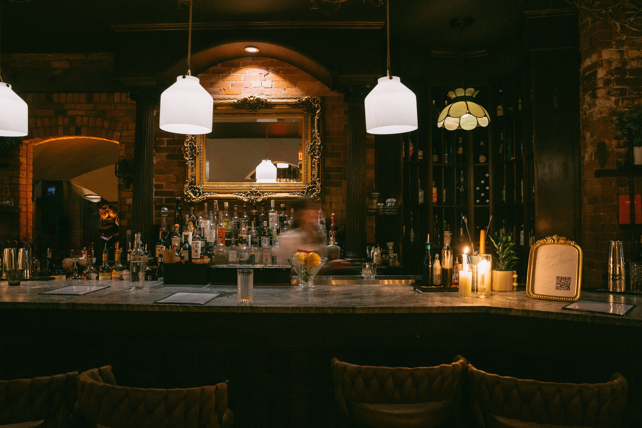 The Alexander bar in warm evening light — candles, brick, and the ornate gold mirror