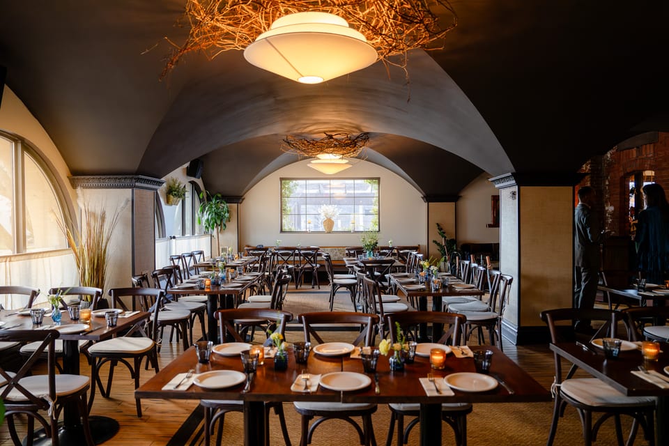 The Alexander dining room with vaulted ceiling, set tables, and warm natural light