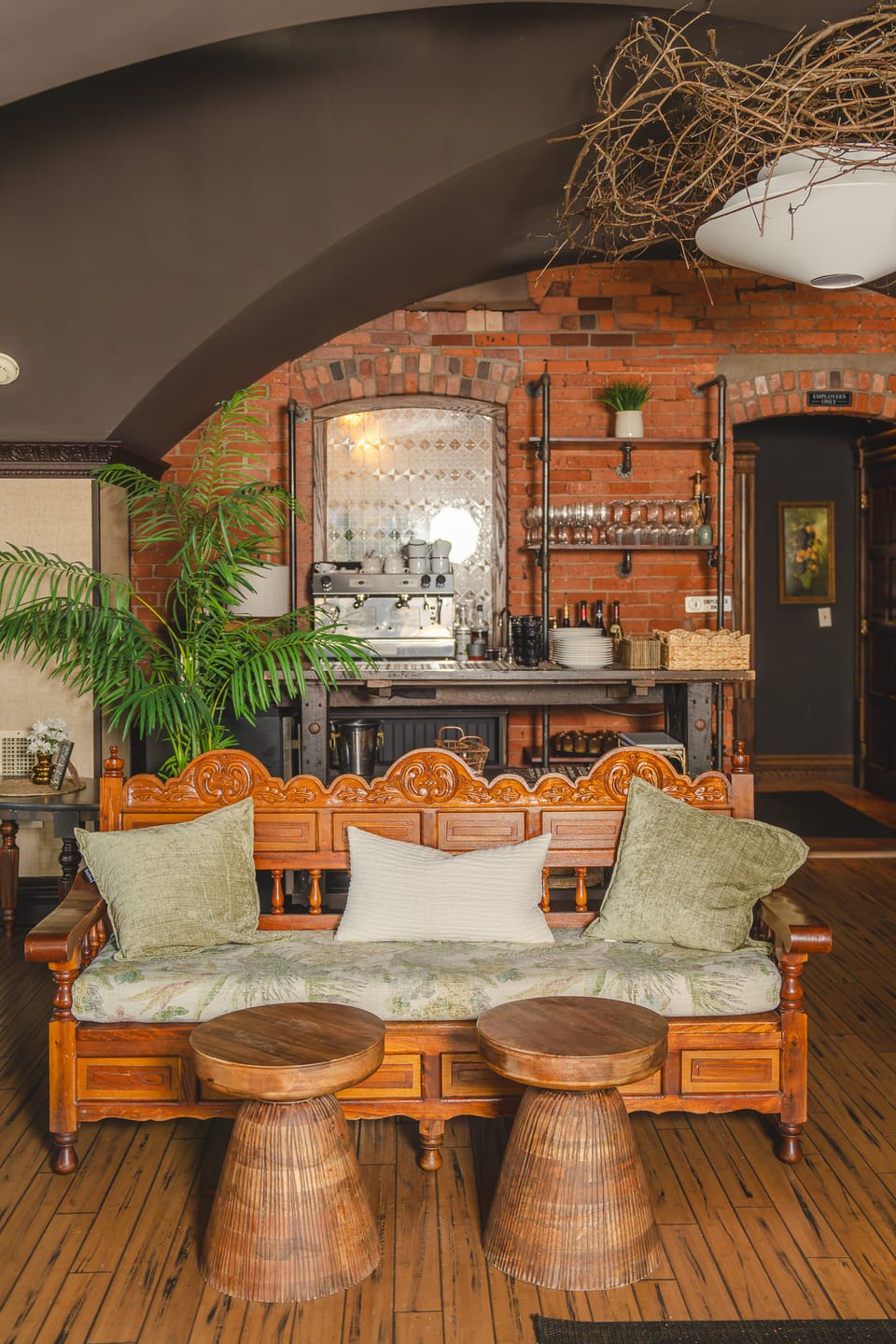Antique wooden bench with green pillows under the brick archway near the espresso bar