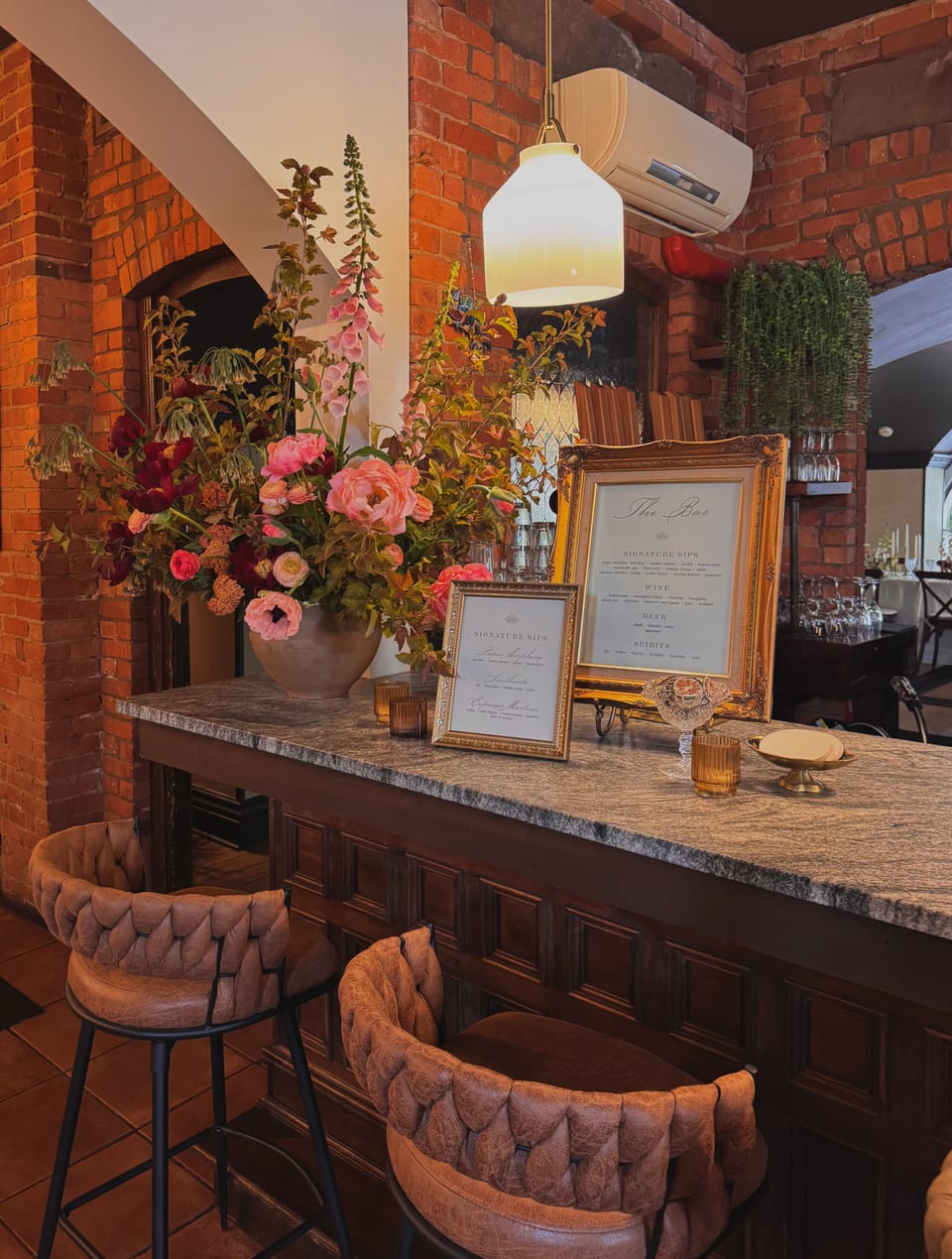 Bar dressed with abundant foxglove and rose arrangement and a framed cocktail menu