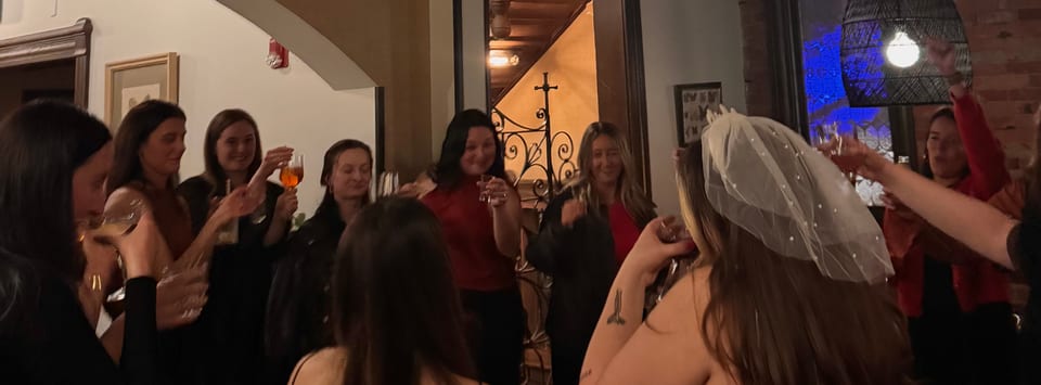 Bride in veil surrounded by friends raising champagne in a candlelit toast