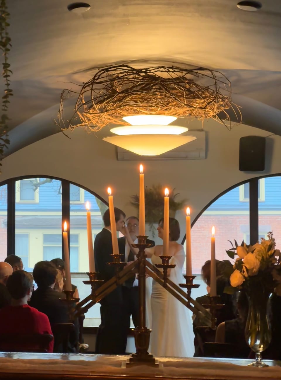 Wedding ceremony with tall brass candelabras framing the couple, grapevine chandelier overhead
