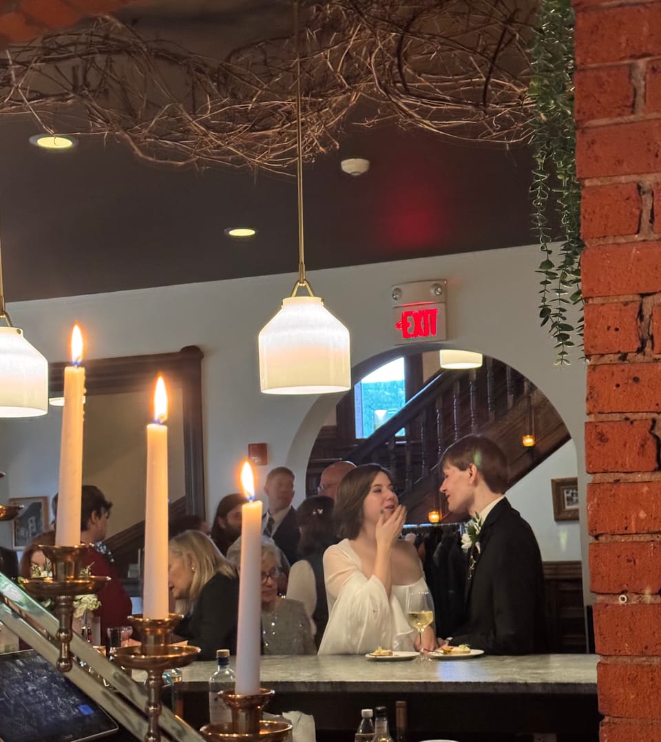 Bride and groom sharing a quiet moment at the bar under a hanging grapevine and pendant lights