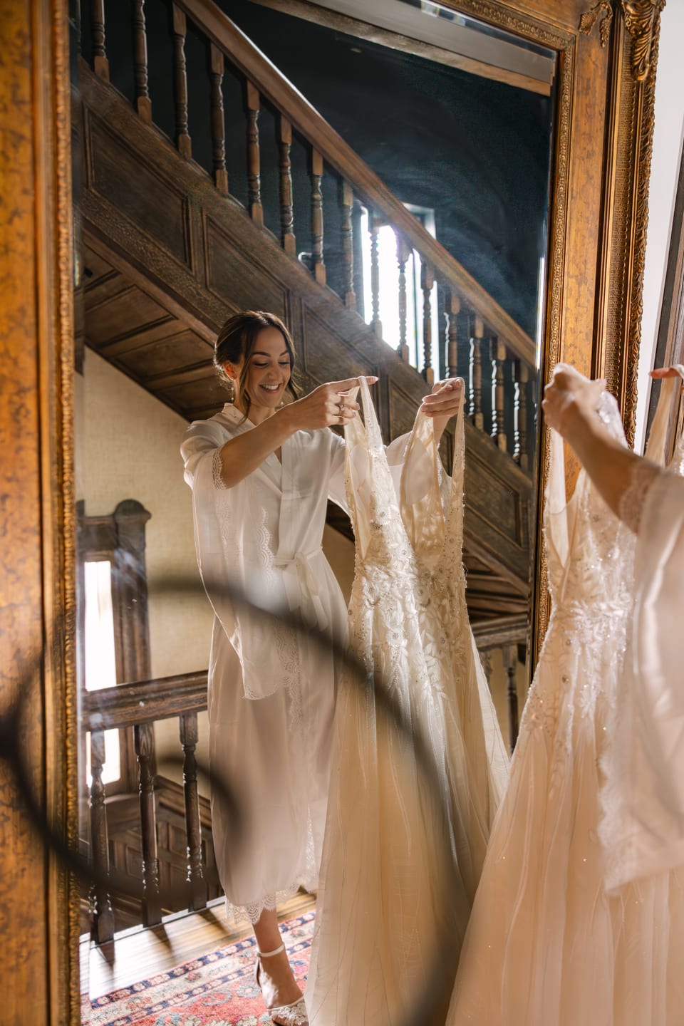 Bride hanging her wedding dress on the staircase mirror — getting ready